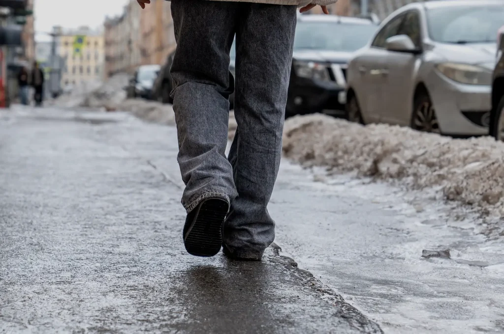 A person walking down a bleak snowy sidewalk in winter